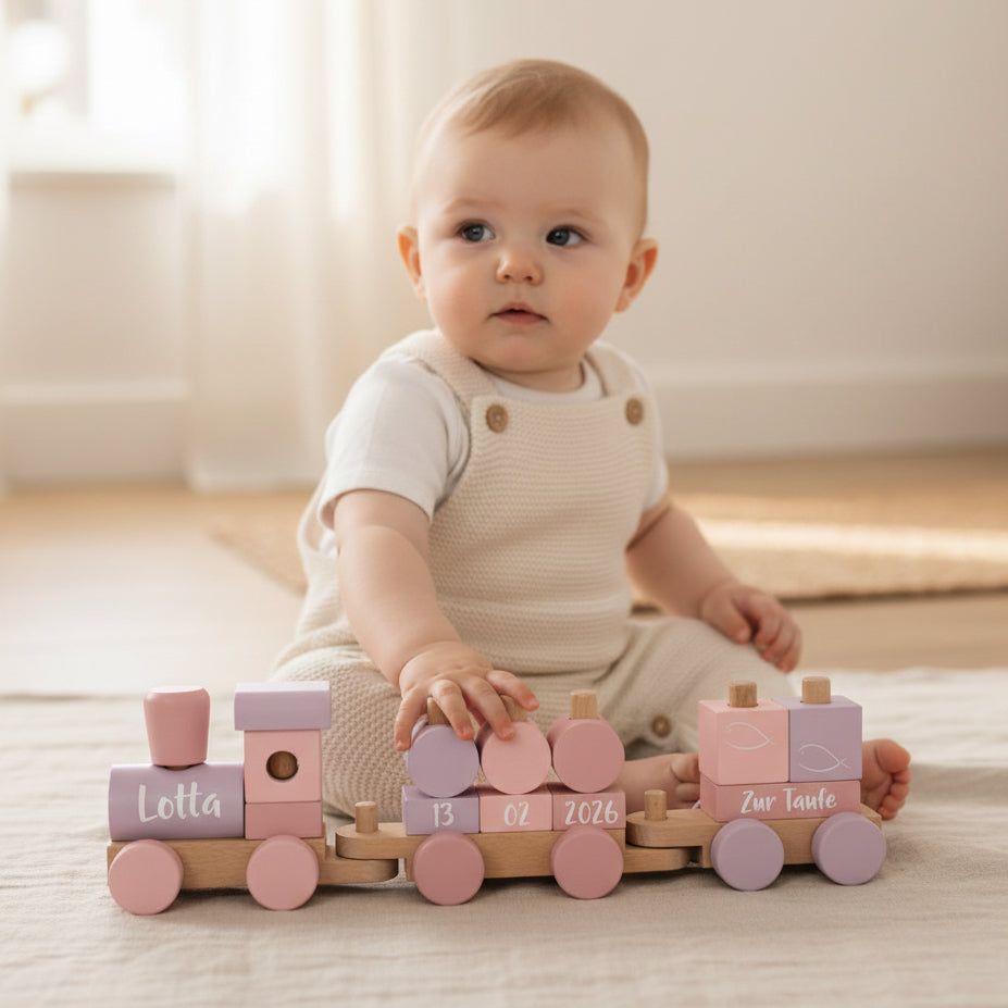 Kind spielt mit personalisiertem Holzzug in Rosa zur Taufe mit Name, Taufdatum und Schriftzug Zur Taufe