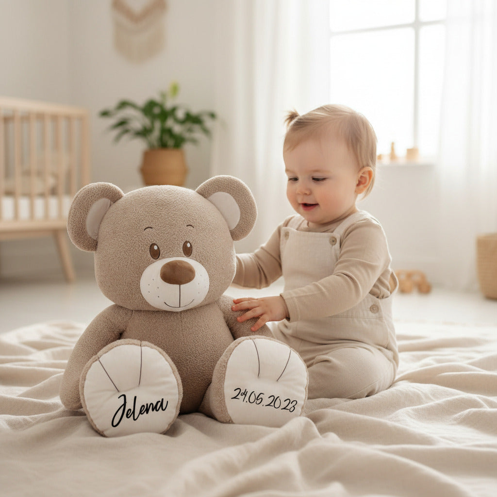 Baby spielt im Kinderzimmer mit personalisiertem XXL Teddybär als liebevolles Geschenk zur Geburt mit Namen bei Schmatzepuffer