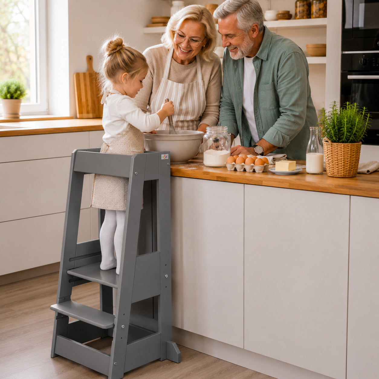 Kind steht im grauen tiSsi Lernturm Felix an der Küchenarbeitsplatte und backt gemeinsam mit den Großeltern